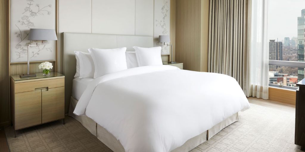 Soft white queen bed sheets with plush pillows in a cozy bedroom.
